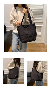 Detailansicht einer großen schwarzen Nylon-Tragetasche mit Modeetikett an der Seite