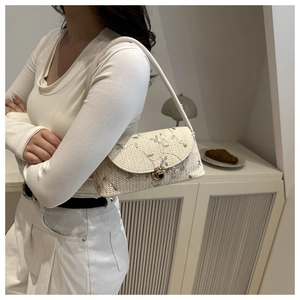 Close-up of cream woven handbag featuring delicate floral embroidery and gold metal buckle
