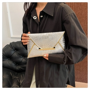 Detail of silver crocodile-embossed envelope clutch with sleek gold metal bar lock