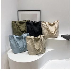 Détail de cabas minimalistes en quatre couleurs sur des supports géométriques