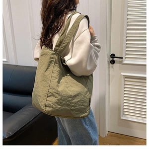 Olive green nylon tote bag on shoulder showing large capacity and soft texture