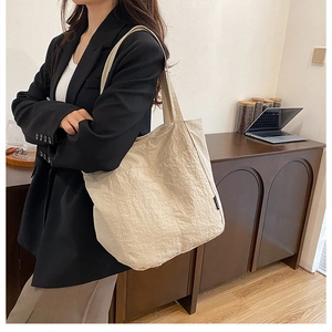 Détail d'un grand sac cabas beige avec texture plissée et étiquette de marque