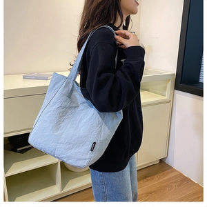 Détail du sac fourre-tout en nylon bleu clair montrant la texture et l'étiquette FASHION