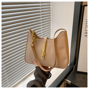 Détail d'un sac bandoulière beige avec chaîne dorée et fermoir métallique élégant