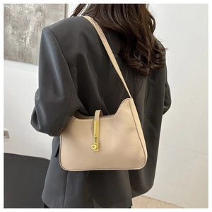 Détail du sac hobo beige avec boucle dorée sur un mannequin en blazer gris