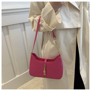 Sac sous le bras en cuir rose tendance avec boucle dorée sur un trench-coat beige clair