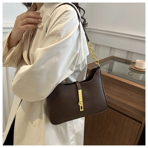 Détail du sac sous le bras en cuir marron foncé avec boucle et chaîne en métal doré