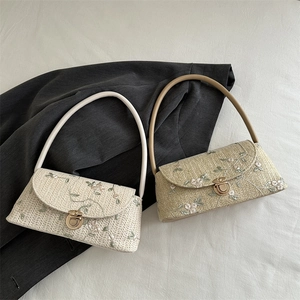 Floral embroidered straw underarm bag with metal clasp and woven bow detail