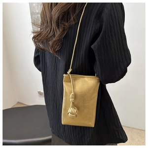 Detail of champagne gold metallic phone bag with woven knot and pleated texture