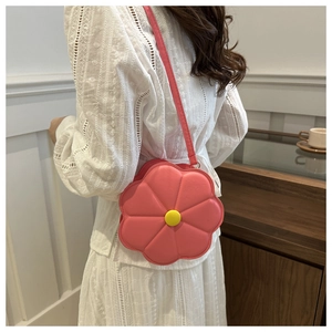Détail d'un sac à bandoulière en cuir en forme de fleur rose avec un centre jaune vif