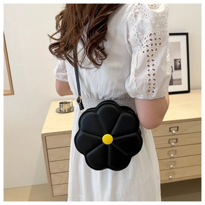 Détail d'un sac bandoulière floral noir avec centre jaune porté par un mannequin en intérieur
