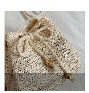 Detail of woven straw bucket bag showing cotton drawstring, wood beads and tassel accents