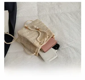 Straw bucket bag interior showing capacity for a pink wallet and smartphone