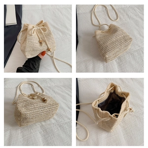 Detail view of woven straw bucket bag with drawstring closure and dark beaded accents
