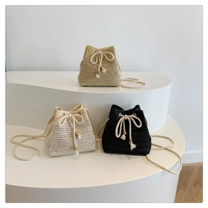 Detail of straw woven bucket bags with drawstring closure and wood bead accents