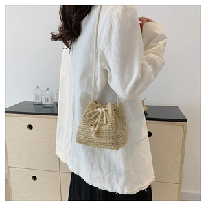Detail of hand-woven straw bucket bag with drawstring closure and wooden bead accents