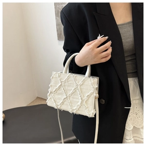 Close-up of quilted white denim crossbody bag with frayed edges and textured fabric
