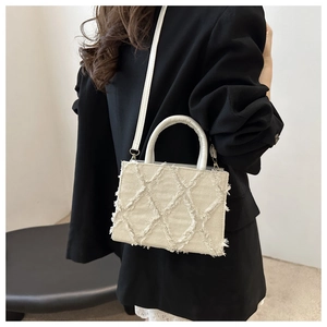 Quilted denim crossbody bag in cream white with frayed edges and dual carry straps
