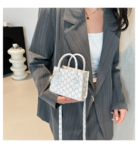 Detail of white mini square bag with M-letter print, twin handles and shoulder strap