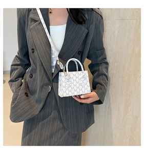 Mini white crossbody bag with grey M pattern shown on a grey striped blazer
