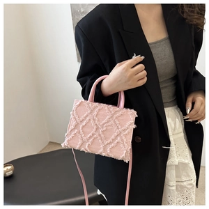 Detail of pink fringed denim handbag with textured tassels and crossbody strap detail