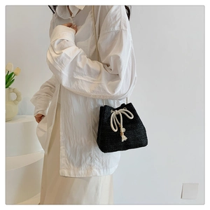 Detail of black woven bucket bag showing textured straw material and cotton drawstring cord