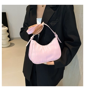 Detail der hellrosa Halbmond-Tasche mit Steppmuster, gehalten von Model im schwarzen Anzug