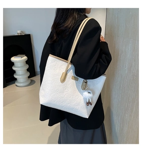 Détail du sac fourre-tout en similicuir blanc avec motifs gaufrés 3D et pompon en peluche