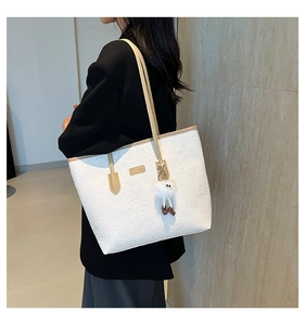 Détail du sac cabas blanc gaufré avec motifs de dessins animés et breloque monstre en peluche