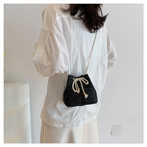 Detail of black woven bucket bag with white rope drawstring and wooden bead accents