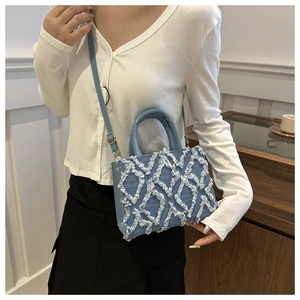 Detail of light blue denim crossbody bag featuring vintage quilted fringe pattern texture