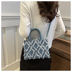 Close-up of denim diamond lattice handbag with fringe details on a fashion model