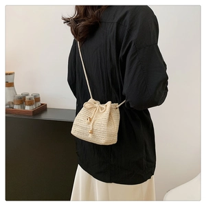 Detail of hand-woven straw bucket bag with drawstring and wooden bead accents