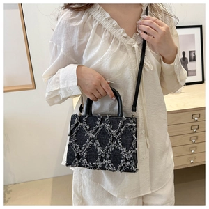 Detail of quilted denim crossbody bag with frayed edges and polished black handles