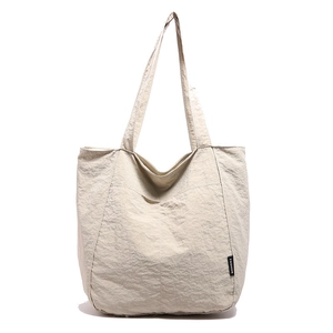Grand sac cabas crème avec texture plissée et étiquette mode pour un usage décontracté