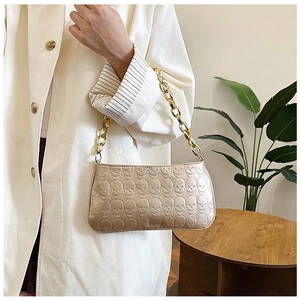 Detail of champagne gold bag with embossed skull patterns and chunky metal chain strap