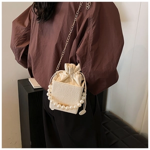 Detail of cream mini bucket bag with pearl handle and golden chain on model
