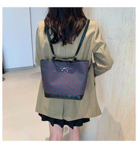 Rear view of a model wearing the blue polka dot tote bag with leather strap detailing