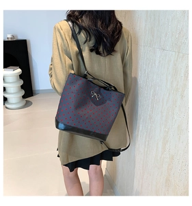 Detail of grey bucket bag featuring red heart patterns and a silver bow on the front