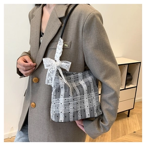 Detail of grey plaid shoulder bag with vintage lace overlay and large white bow