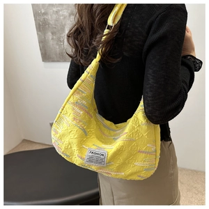Detail of yellow striped embroidery on jacquard shoulder bag with metal strap buckle