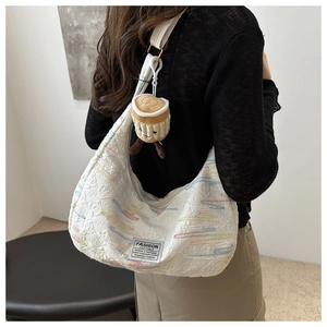Dettaglio della borsa hobo bianca trapuntata con strisce colorate e ciondolo a tazza