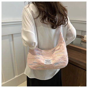 Detail view of pink diamond-textured fabric bag with colorful rainbow stripes and label