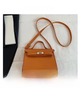 Detail of orange-brown crocodile pattern mini square bag shown with smartphone for scale