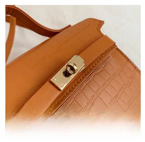 Close-up of brown crocodile texture leather bag with a luxury gold metal rotary lock