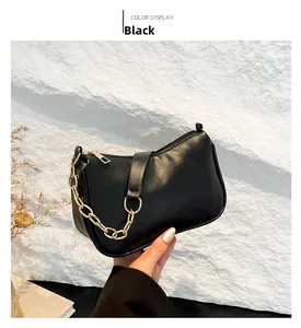 Detail of a black minimalist underarm bag with decorative gold chunky chain and matte finish