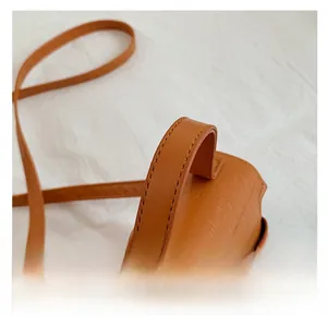 Detail of a brown crocodile embossed handbag featuring a reinforced wide top handle