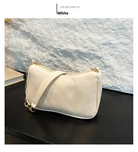 Detail of white baguette shoulder bag featuring smooth leather and decorative gold chain