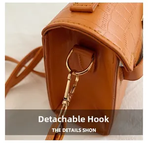 Macro view of detachable gold hook and crocodile texture on brown handbag
