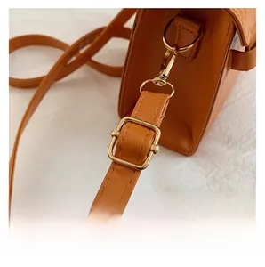 Detail of uniform stitching and metal buckle on the brown leather shoulder bag strap